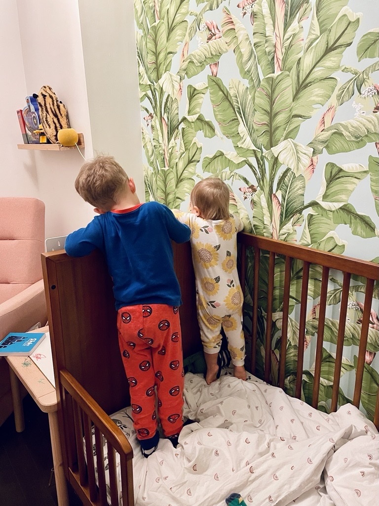 two young boys standing on a bed wearing pyjamas
